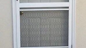 Una porta amb estructura blanca, un panell de vidre i un estriatge de benvinguda.