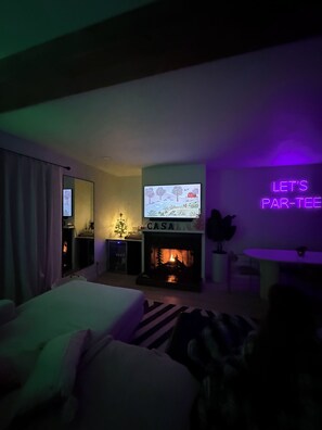Habitación de hotel con televisión, chimenea y un letrero de neón en la pared.