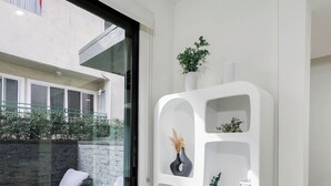 Un intérieur moderne avec une étagère blanche, une porte vitrée donnant sur un espace extérieur et un coin salon.
