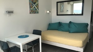 Una habitació amb un llit, un escriptori, dues cadires, un mirall fixat a la paret i un quadre.