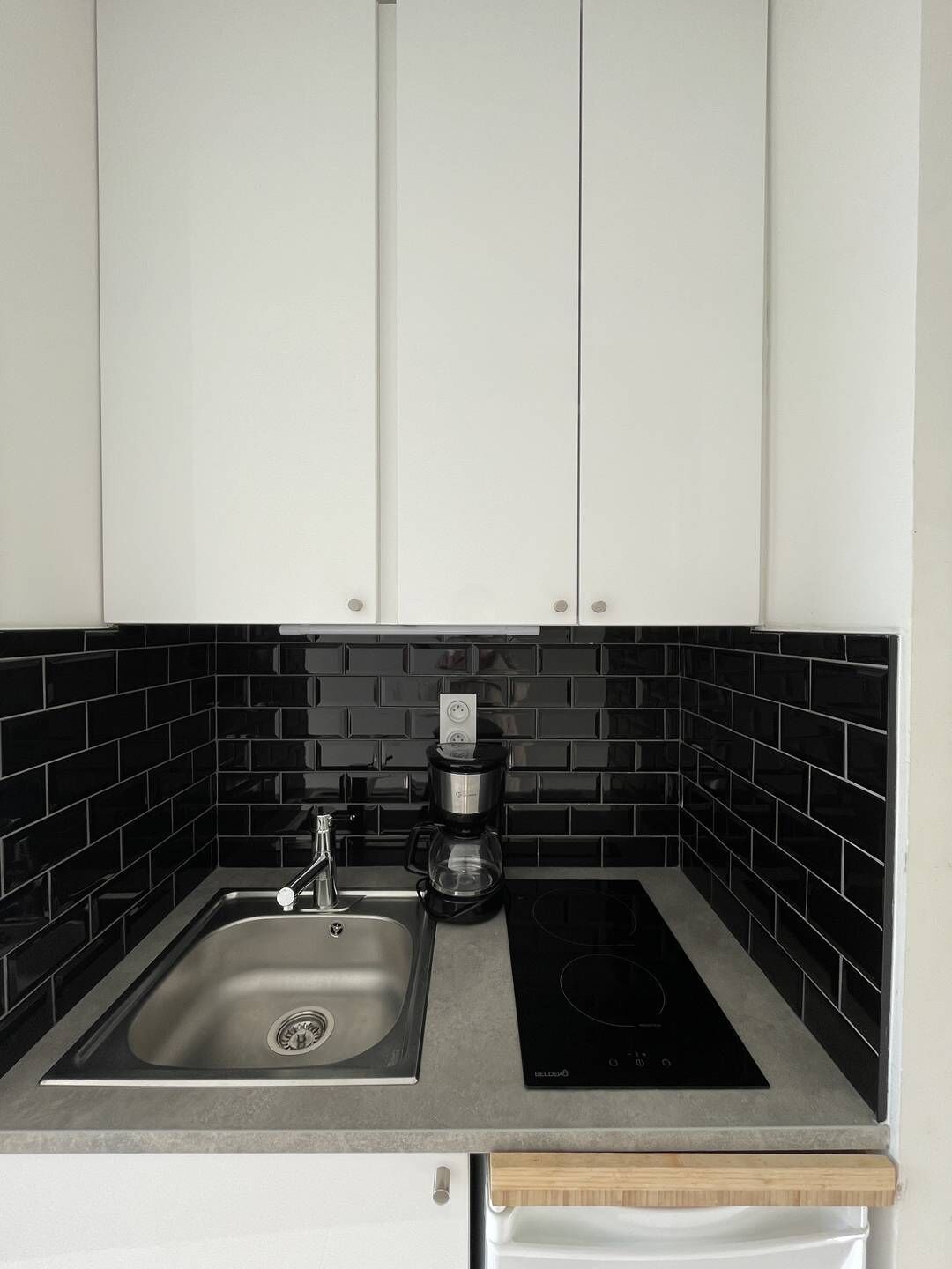 A kitchen with a sink, a coffee maker, and a black induction cooktop.