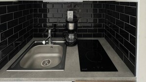 Cuina amb rentatge, cafetera i fogó d'inducció negre.