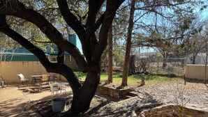 A patio area with a large tree, outdoor furniture, and a stone planter.