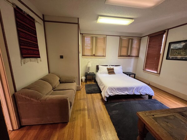 A room with a bed, a sofa, a small table, and a window with blinds. - 3-BR house with private park in great central location (Sweetwater)