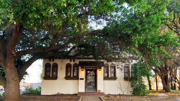 A building with a central entrance, a covered porch, and a pathway leading to it.