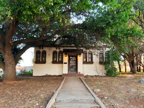 A building with a central entrance, a covered porch, and a pathway leading to it. - 3-BR house with private park in great central location (Sweetwater)