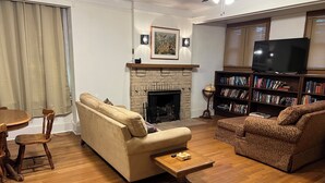 A living room with a fireplace, sofa, coffee table, bookshelf, and a television.