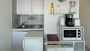 A compact kitchen with a refrigerator, microwave, coffee maker, and a clock on the wall. - Port Nature Studio 627 - 3 people (AGDE)