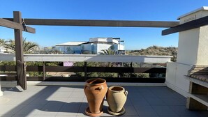 A rooftop terrace with a pergola, two terracotta pots, and a view of a building with a white facade and a blue sky. - DUNE - Villa Port Nature 66 - Luxury - 4 people (AGDE)