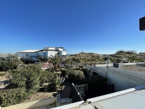 Een gebouw met een plat dak, omgeven door groen en een heldere lucht.