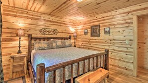 A wooden cabin bedroom with a bed, nightstands, and a bench. - Bear Paw 1/1! Pool Table! Near Helen (Clarkesville)