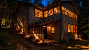 A two-story wooden house with large windows, a porch, and a well-lit interior. - Bear Paw 1/1! Pool Table! Near Helen (Clarkesville)