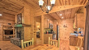 A wooden cabin interior with a dining area, kitchen, and fireplace. - Bear Paw 1/1! Pool Table! Near Helen (Clarkesville)