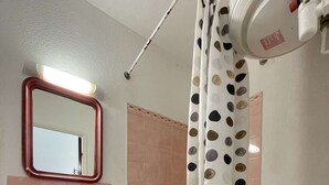 Un baño con lavamanos, espejo, cortina de ducha e inodoro.