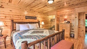 Ein Zimmer in einer Holzhütte mit einem Bett, einem Nachttisch, einem Schminktisch und einer Bank.