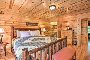 Ein Zimmer in einer Holzhütte mit einem Bett, einem Nachttisch, einem Schminktisch und einer Bank.