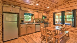 Ein Holzblockhaus-Interieur mit Küche, Esstisch und Bänken.