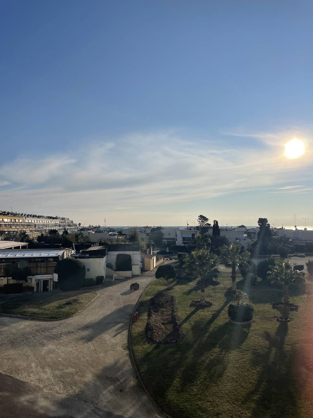 Een kustgebied met gebouwen, een heldere lucht en de zon.