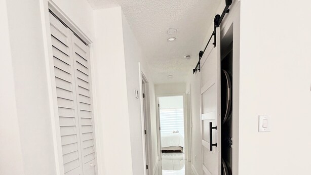A hallway with white walls, a tiled floor, and a door with a black handle. - Beautiful house near marlins stadium (Miami)