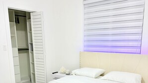 A bedroom with a bed, a nightstand, a lamp, a bedside table, a closet, and a window with blinds. - Beautiful house near marlins stadium (Miami)
