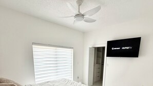 A bedroom with a bed, a ceiling fan, a TV, a window with blinds, and a closet. - Beautiful house near marlins stadium (Miami)