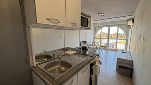Ett litet kök med en diskho, en kaffebryggare och ett litet fönster.