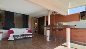 A modern kitchen with a bar area, a sofa, and a dining table. - PINK LADY - Villa Port Nature 12 - Luxury - 4 people (AGDE)