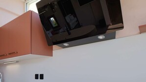 A kitchen with a microwave, a black induction cooktop, and peach-colored cabinets. - PINK LADY - Villa Port Nature 12 - Luxury - 4 people (AGDE)