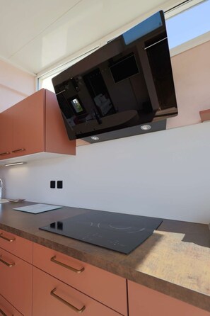 A kitchen with a microwave, a black induction cooktop, and peach-colored cabinets. - PINK LADY - Villa Port Nature 12 - Luxury - 4 people (AGDE)