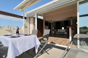 An outdoor dining area with a table set for two, a chair, and a bottle of wine. - PINK LADY - Villa Port Nature 12 - Luxury - 4 people (AGDE)