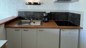 Eine kleine Küche mit Spüle, Herd und Kühlschrank.