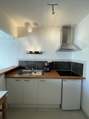 A compact kitchen with a sink, stove, and a small refrigerator. - Villa Port Nature 59 - 2 people (AGDE)