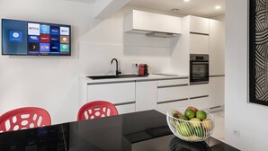 Een moderne keuken met witte kasten, een zwart aanrecht en een schaal fruit.