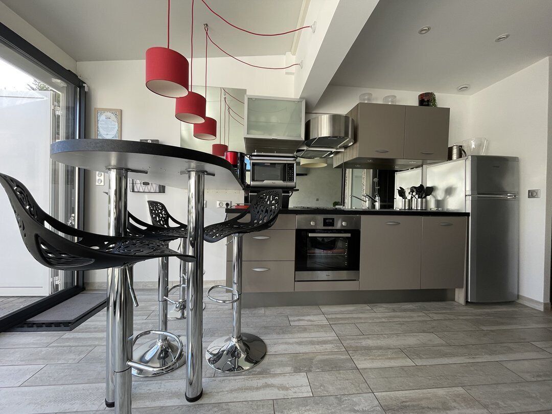 Une cuisine moderne équipée d’appareils électroménagers en acier inoxydable, une table de salle à manger ronde et un tabouret de bar.