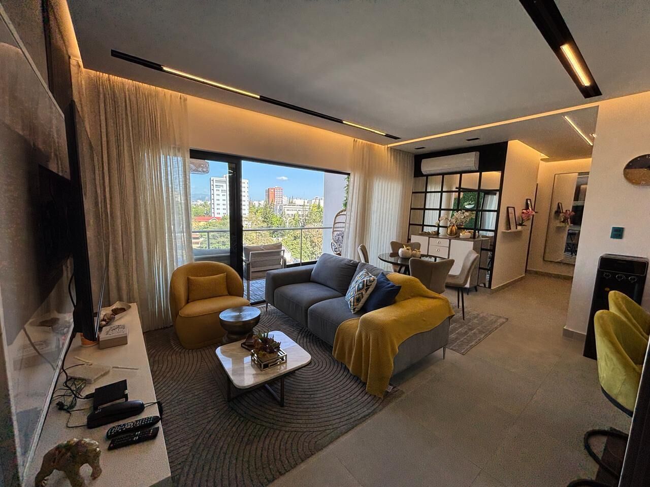 Un salon moderne comprenant un canapé, des fauteuils, une table basse et un téléviseur.