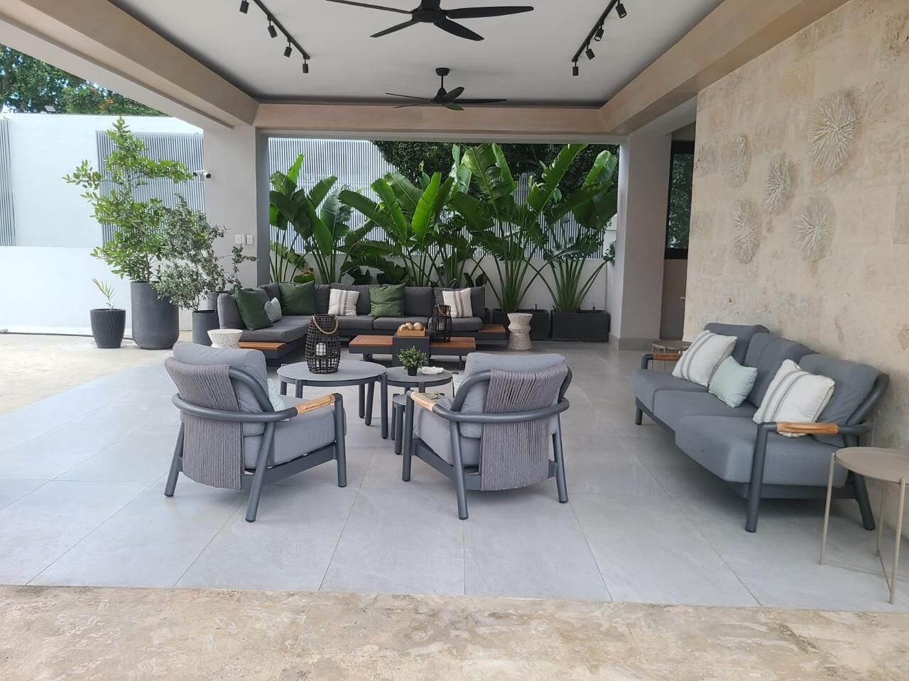 A covered outdoor seating area with a sofa, chairs, and a coffee table.