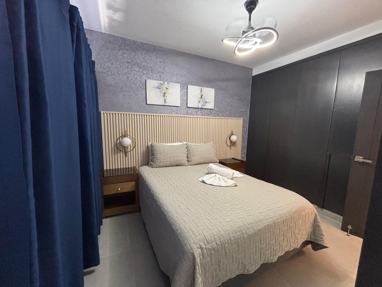 A bedroom with a bed, bedside tables, a wardrobe, and a ceiling light fixture.
