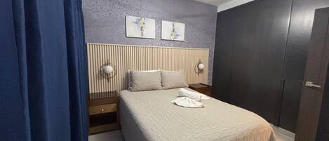 A bedroom with a bed, bedside tables, a wardrobe, and a ceiling light fixture.