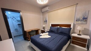 A neatly arranged bedroom with a bed, bedside tables, a desk, and a wardrobe. - De Lujo (Santiago de los Caballeros)