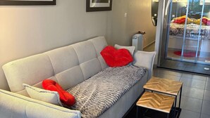 Ett modernt vardagsrum med en soffa, ett litet träbord och två inramade tavlor på väggen.