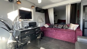 Uma sala de estar moderna com televisão, escrivaninha, sofá e um vaso grande.