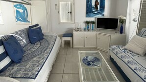 A living room with a sofa, a coffee table, a TV, and a painting on the wall. - Villa Port Nature 134 - 2 people (AGDE)