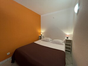 A small, single-bed room with a brown bedspread, two bedside lamps, and a nightstand. - IMAGINE - Villa Port Nature 16 - Classic - 2 people (AGDE)