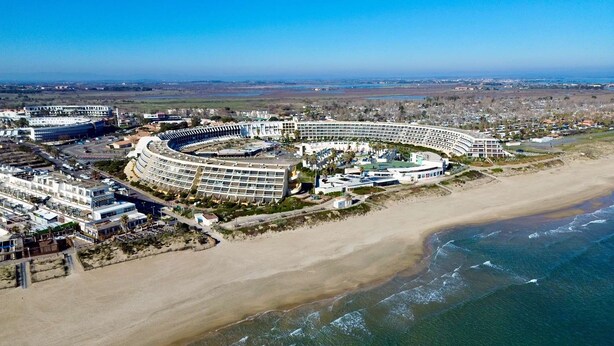 Een hotel aan de kust met een gebogen structuur, direct aan het strand.