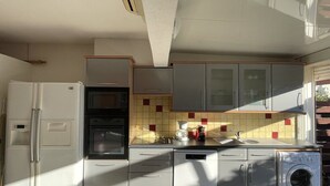 Een kleine keuken met een koelkast, oven, vaatwasser en wasmachine.