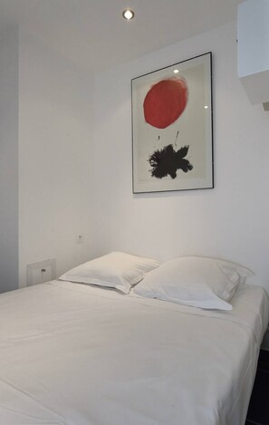 A bedroom with a bed, white pillows, and a framed artwork on the wall. - ELLE  et  LUI - Port Nature Studio 830 - Luxury - 2 people (AGDE)