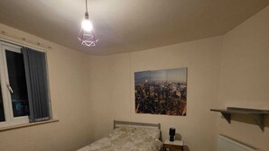 A bedroom with a bed, a window, a radiator, a painting, and a ceiling light. - Room 3 in sheffield (Sheffield)