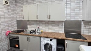 A compact laundry room with a washing machine, dryer, and a sink with a wooden countertop. - Room 3 in sheffield (Sheffield)