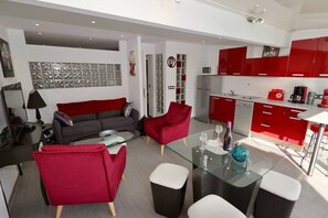 Ein modernes Wohnzimmer mit einem grauen Sofa, roten Sesseln und einem Glastisch.
