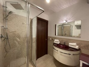 Ein Badezimmer mit Duschkabine, Waschtisch mit Spiegel und Handtuchhalter.